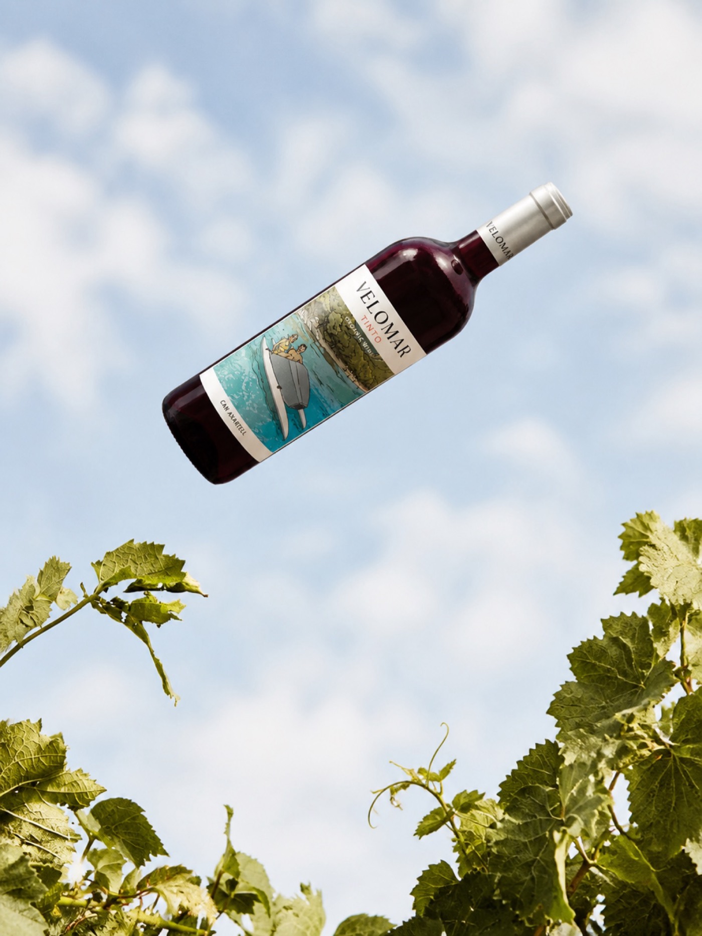 Velomar Tinto bottle tossed above vine leaves against the sky